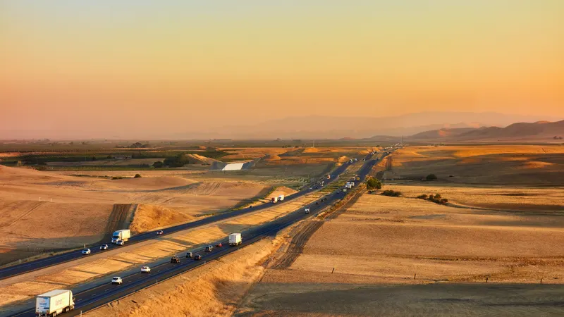 Aerial view of a desert highway with vehicles at sunset
